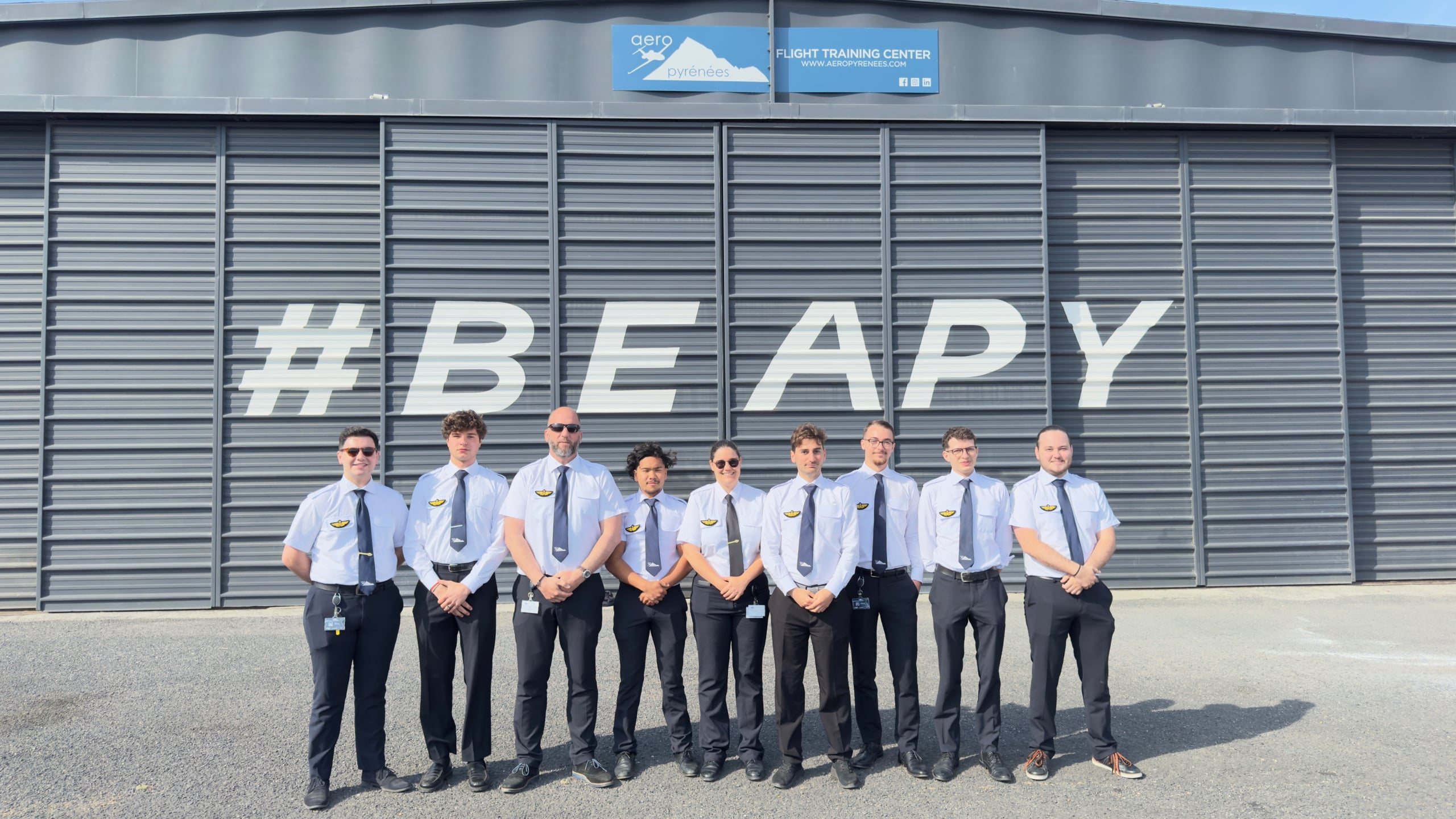 Photo d'élèves pilotes d'Aéropyrénées devant le hangar de l'école